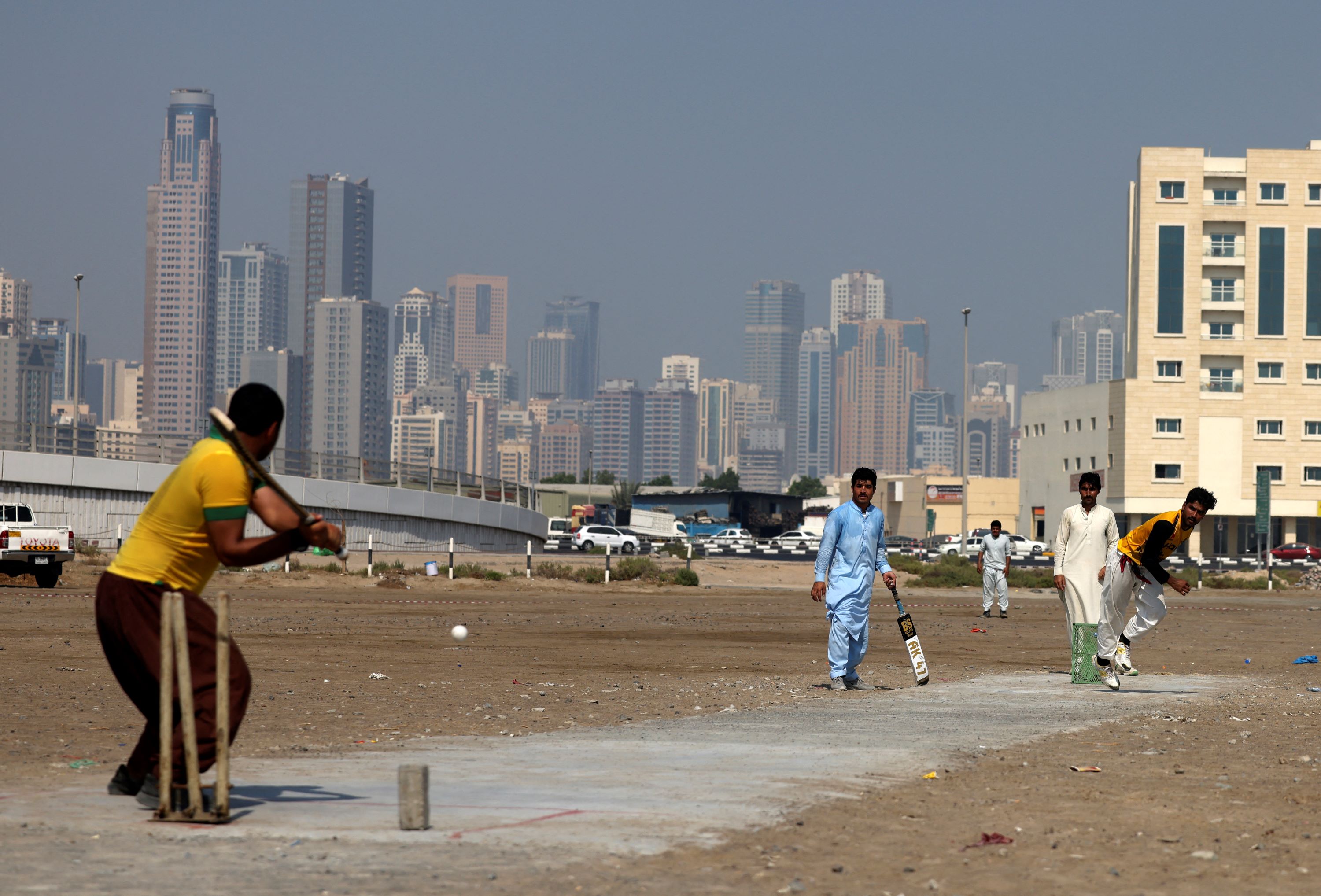 Pakistani workers play cricket in an industrial zone in the Gulf emirate of Sharjah, during their day off from work, on September 24, 2022 (AFP)