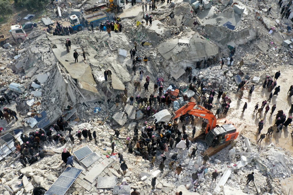 This aerial view shows residents searching for victims and survivors amidst the rubble of collapsed buildings following an earthquake in the village of Besnia near the twon of Harim, in Syria's rebel-held noryhwestern Idlib province on the border with Turkey, on February 6, 2022. 
