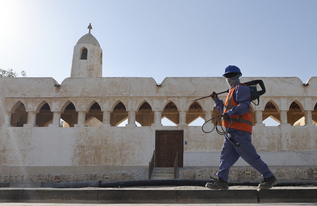 A worker walks past an old traditional structure on the sea promenade of Doha during renovation work in Qatar's capital on 28 November 2022 (AFP)