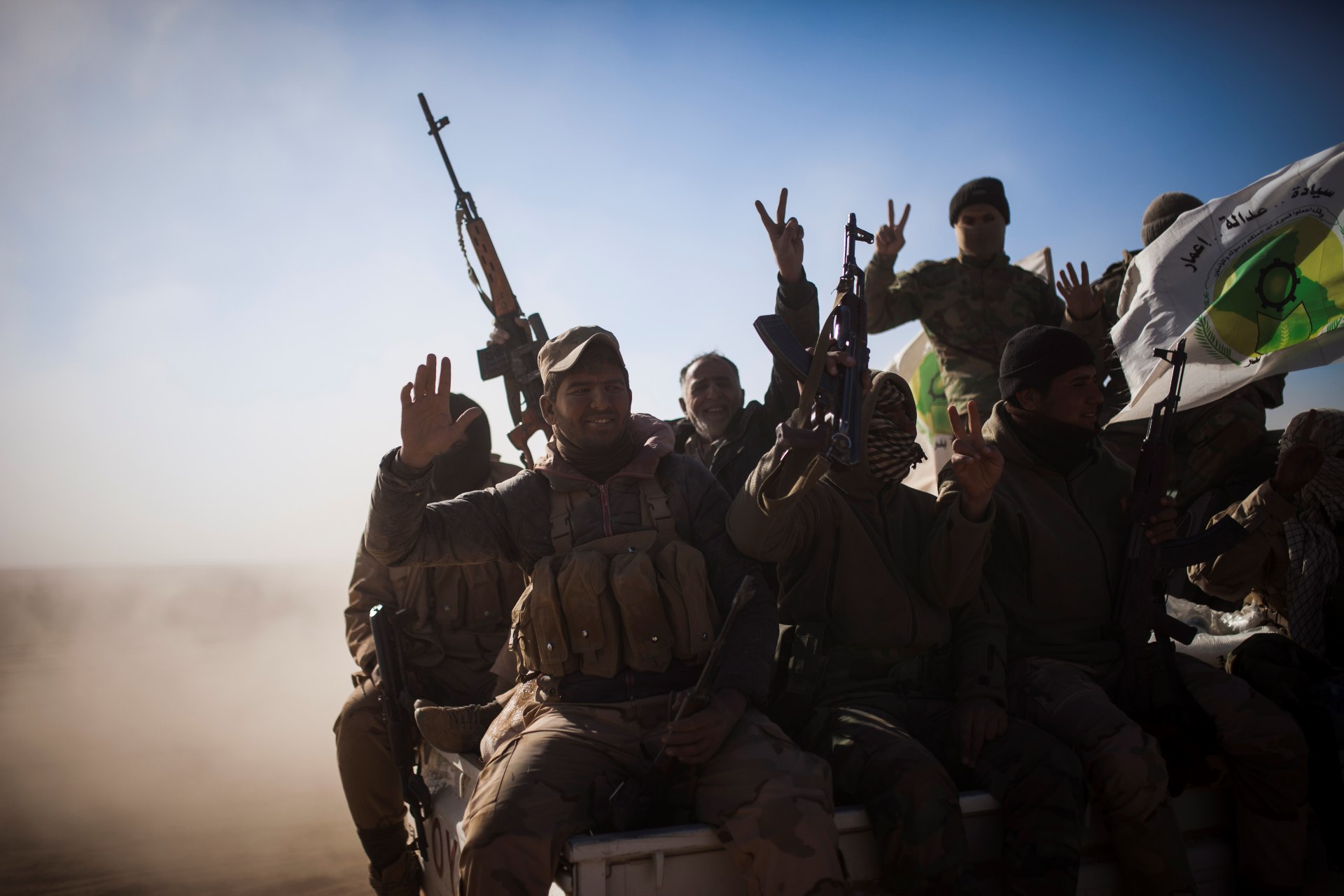 Soldiers of the Hashd al-Shaabi wave the victory sign onboard a pickup truck, on their way to Tal Afar airport in 2016 (AFP)
