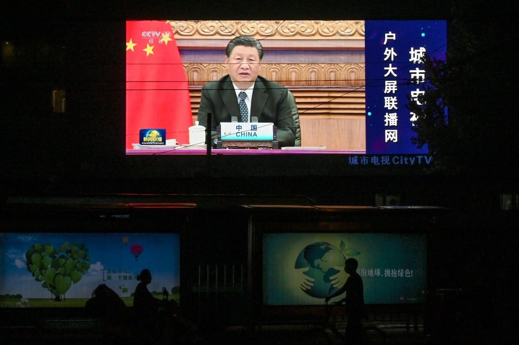 A screen shows a news programme featuring Chinese President Xi Jinping speaking via video at the opening of the virtual BRICS summit in India, on a street in Beijing, on 10 September 2021 (AFP)