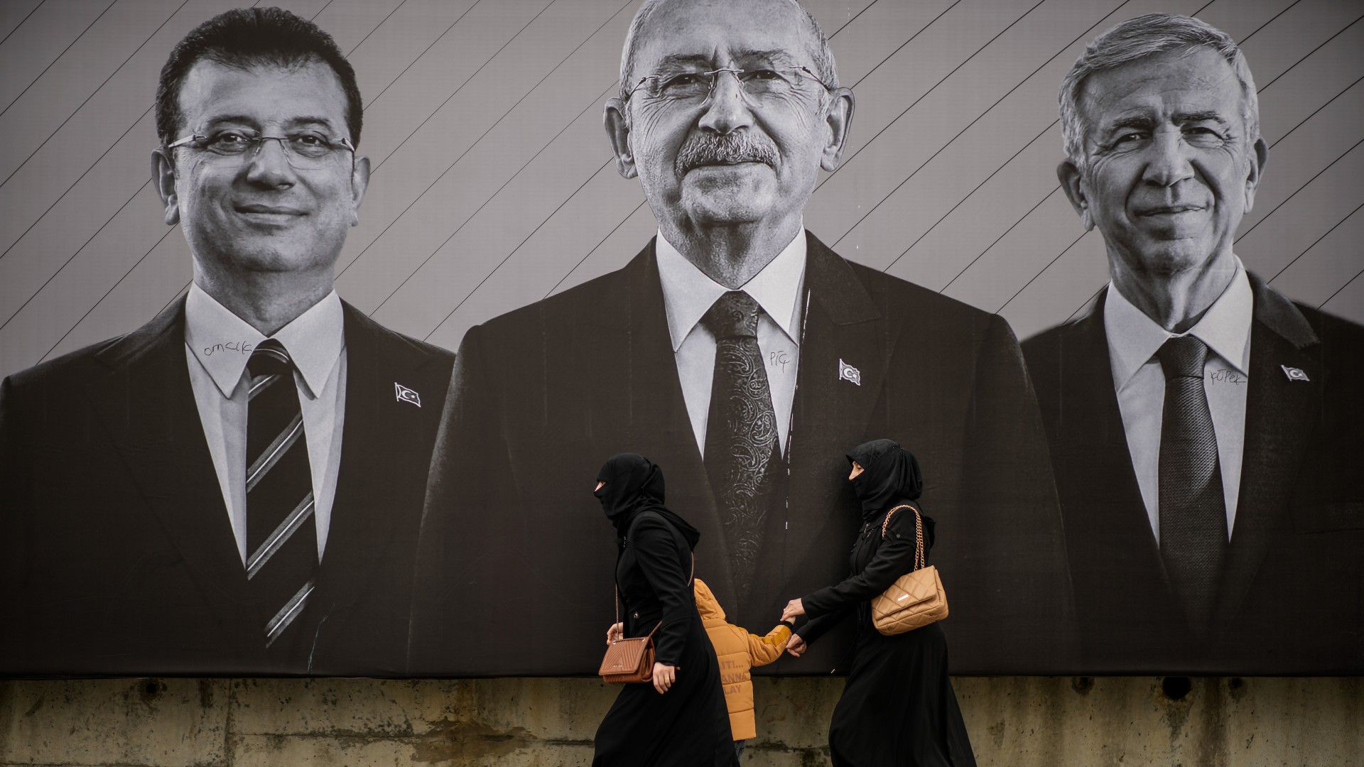 People walk past a campaign billboard of Kemal Kilicdaroglu, centre, Istanbul Mayor Ekrem Imamoglu, left, and Ankara Mayor Mansur Yavas in Istanbul (AP)