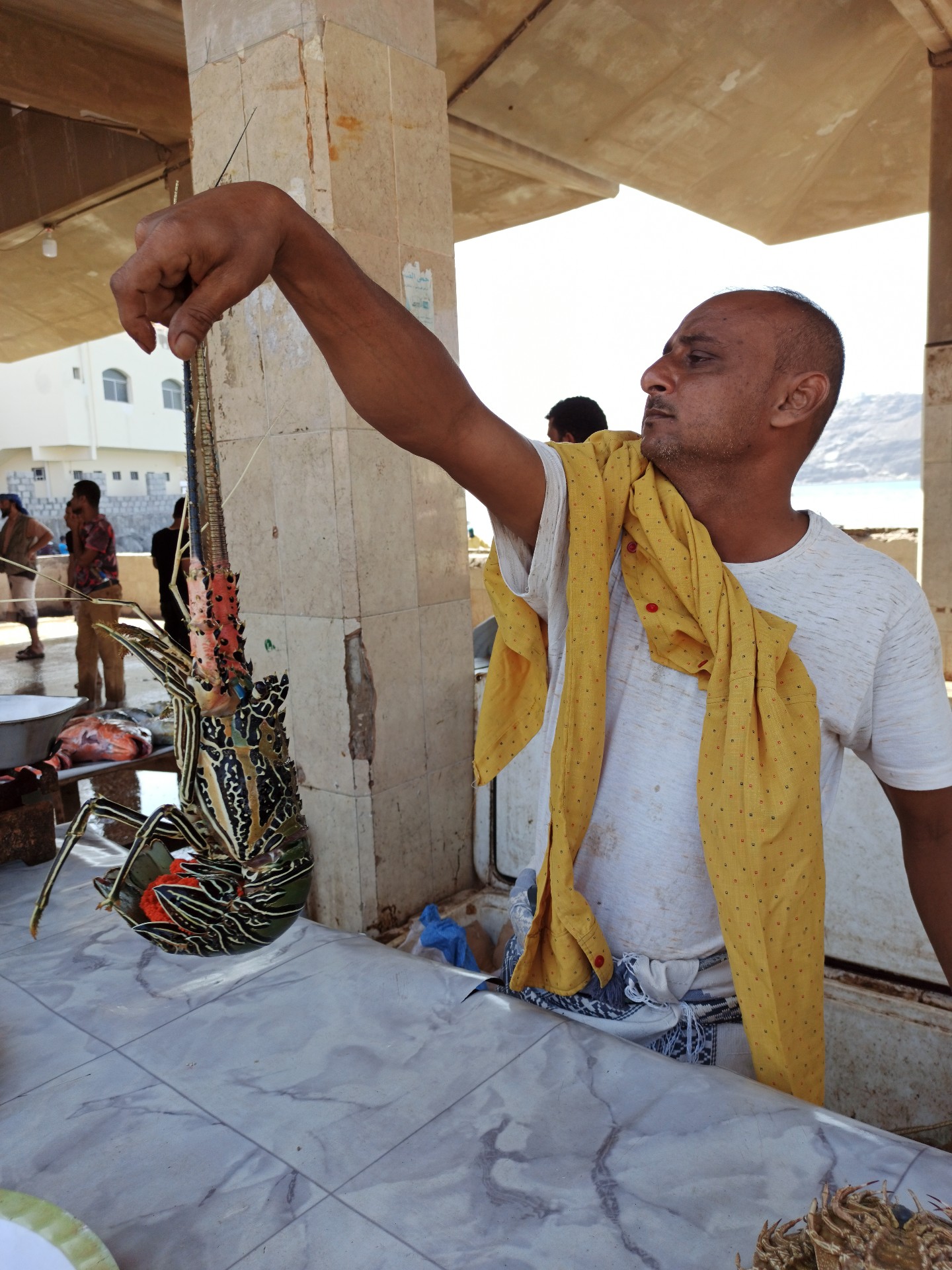 A fisherman sells a lobster in Aden province's Sirah, southern Yemen (MEE)