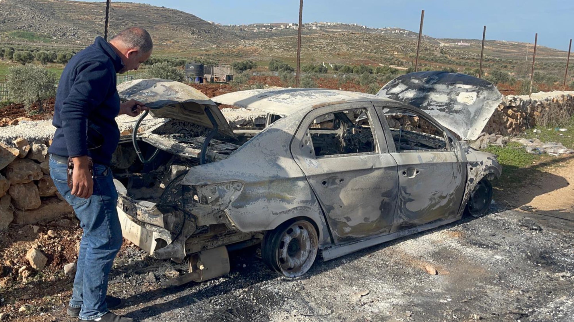 A Palestinian inspects a car that was vandalised by Israeli settlers in the Palestinian village of Jalud, southeast of Nablus, 30 January 2023 (MEE/Amir Halmi Shaheen)