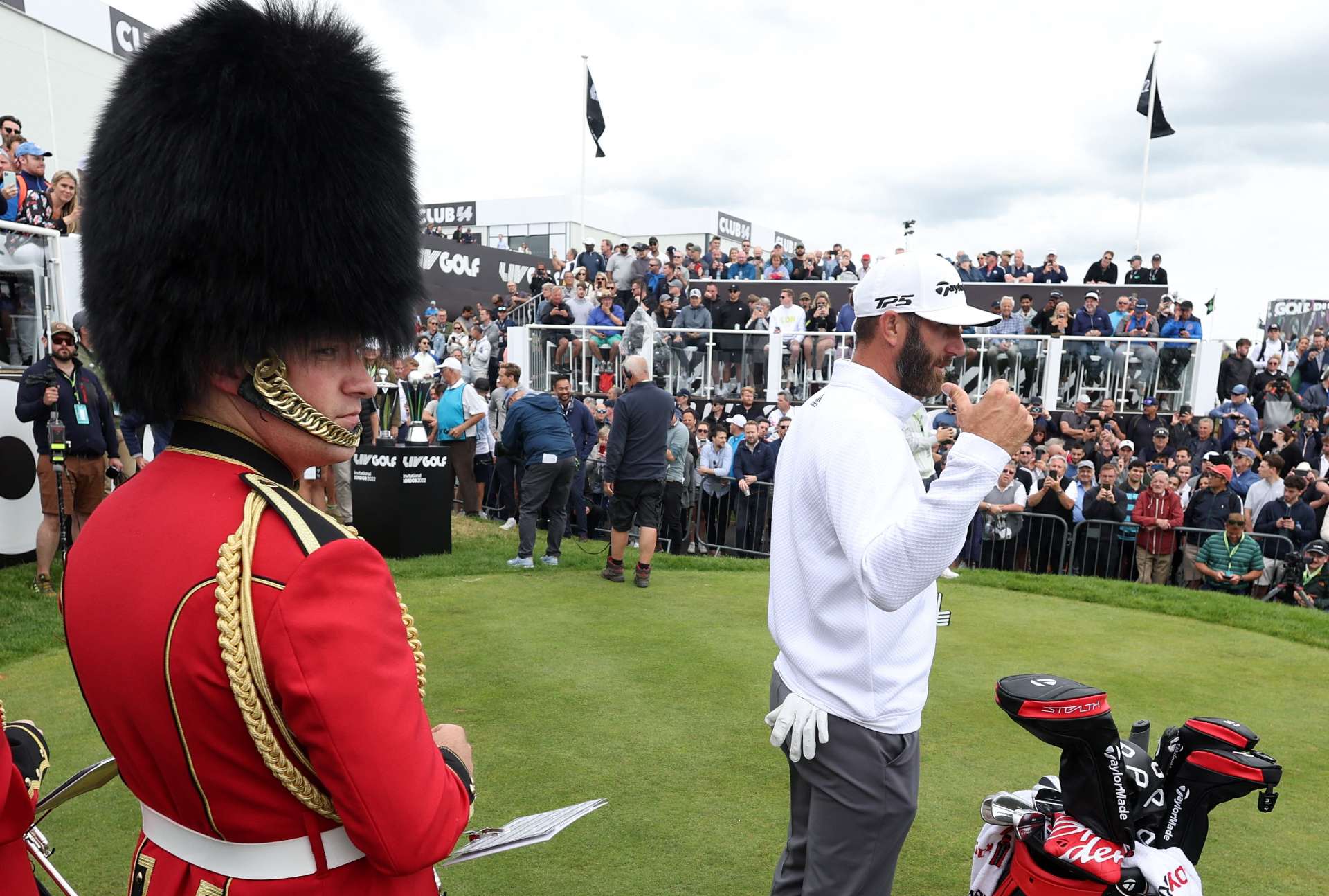 Dustin Johnson is watched by a member of brass band dressed in a costume resembling the uniform of the Grenadier Guards (Reuters)