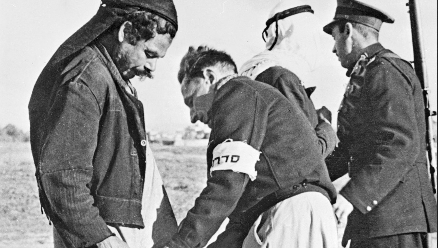 Members of Haganah search two Palestinians at the Tel Aviv gate on 20 January 1948 (AFP)