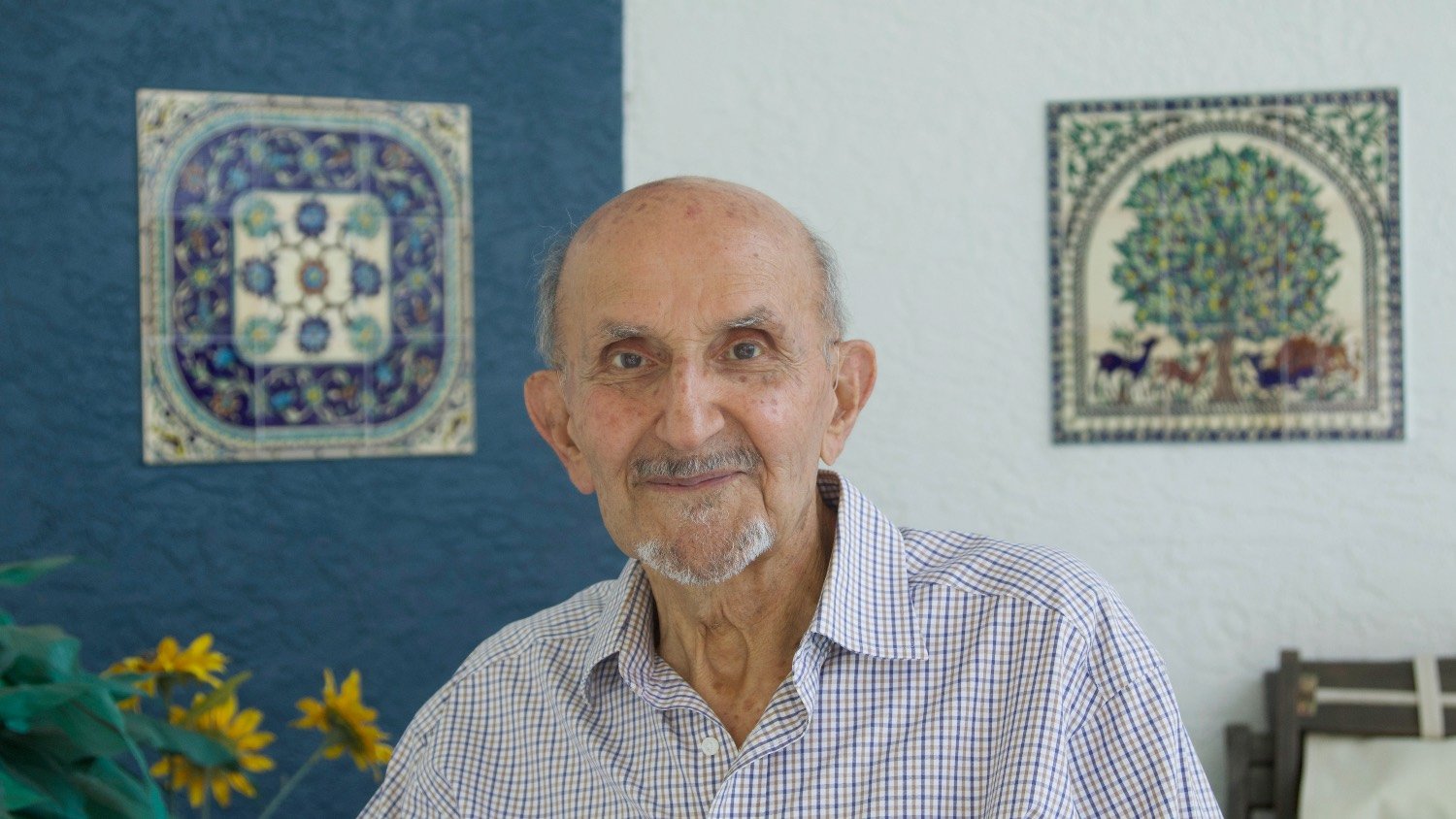 Hassan Hammami stands in front of a set of two tile art pieces he bought from Palestine.