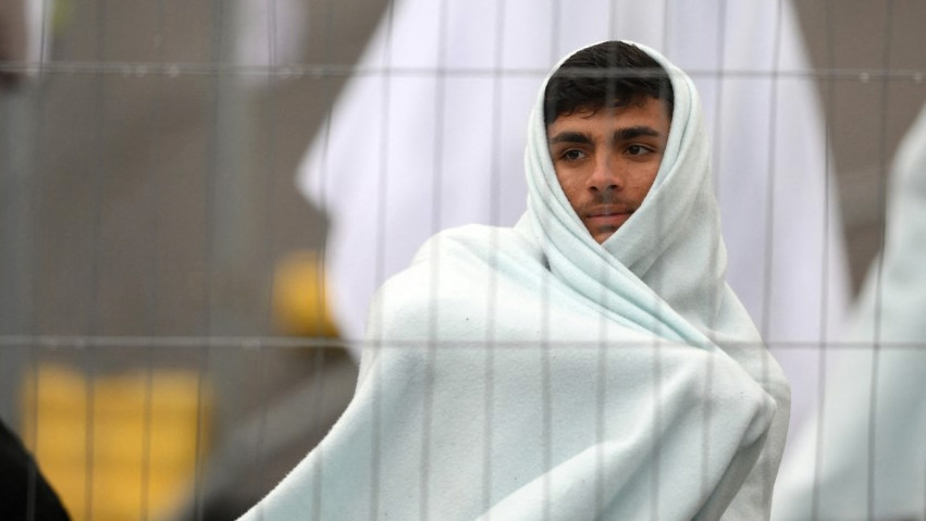 Detainees are seen wrapped in blankets inside the Manston short-term holding centre for migrants, near Ramsgate, southeastern England, on 3 November 2022 (AFP)