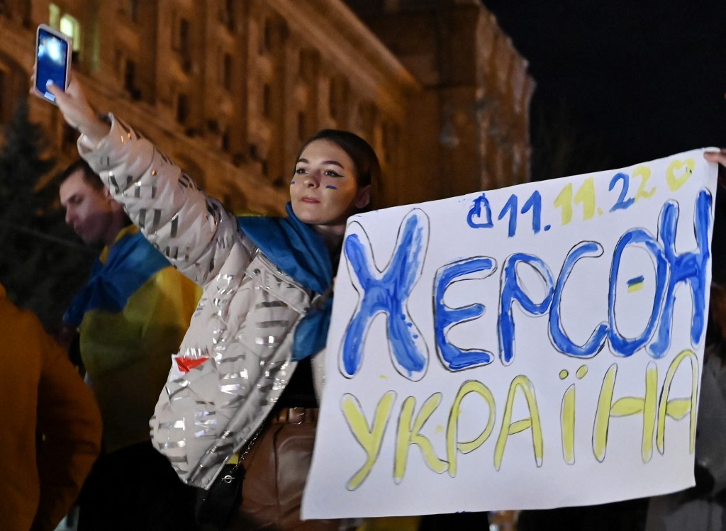 A woman holds a sign reading “Kherson Ukraine” to mark the city’s liberation on 11 November 2022 in Kyiv (AFP)