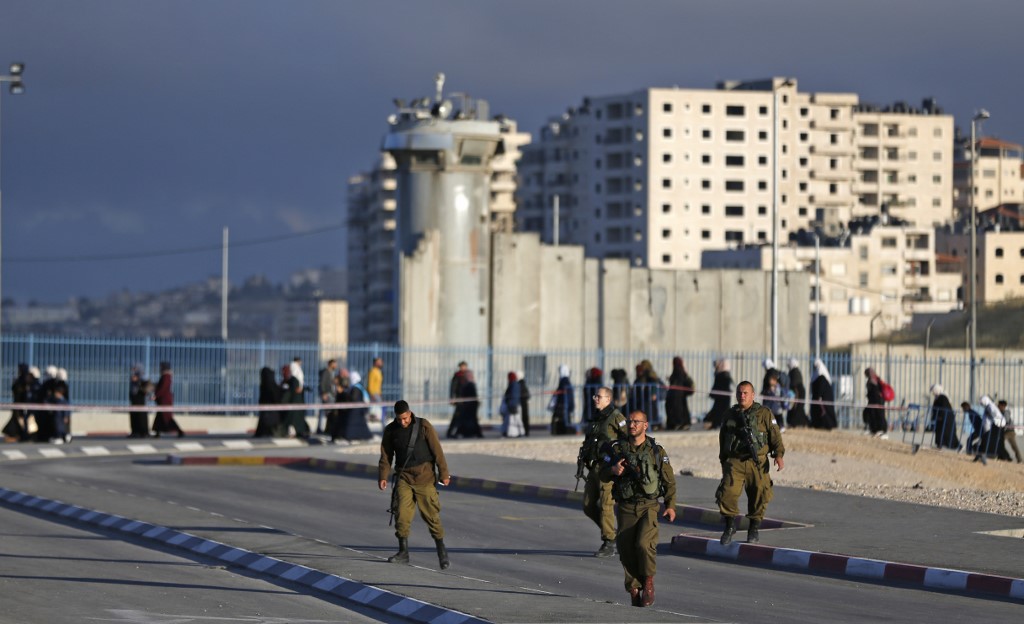 Israeli soldiers walk near Jerusalem’s Qalandia checkpoint on 10 May (AFP)