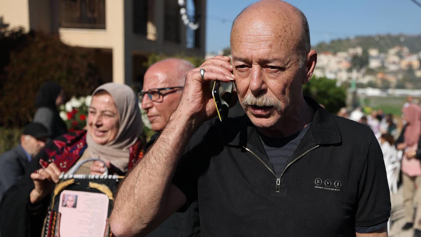 Maher Younis, a Palestinian released from Israeli jails after 40 years, speaks on a mobile phone as he stands next to his cousin Karim Younis, 19 January 2023 (AFP)