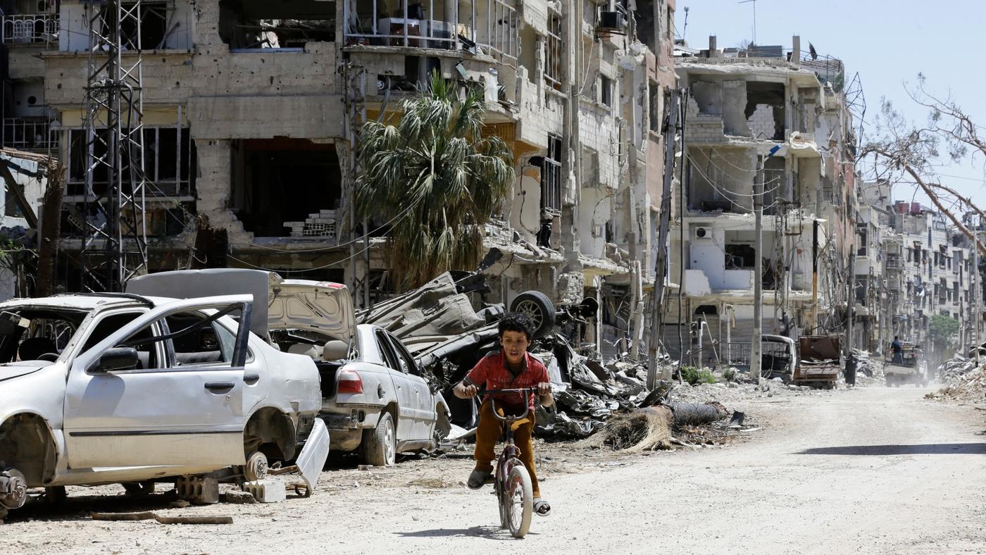 A Syrian boy cycles down a destroyed street in Douma on the outskirts of Damascus on 16 April 2018 (AFP)