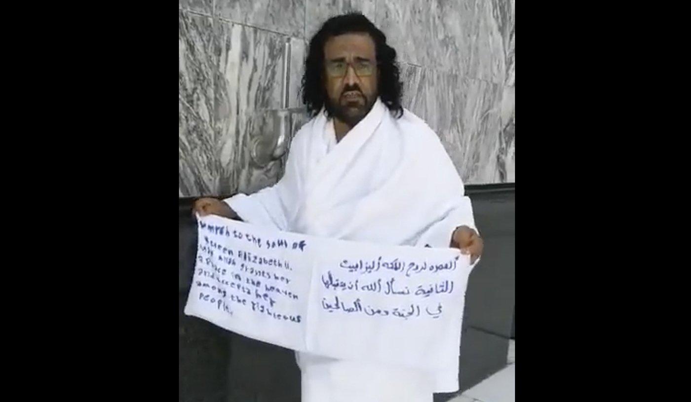 A screengrab from a social media video showing a Yemeni national in Mecca holding a banner that reads: “Umrah for the soul of Queen Elizabeth II, we ask Allah to accept her in heaven and among the righteous." 