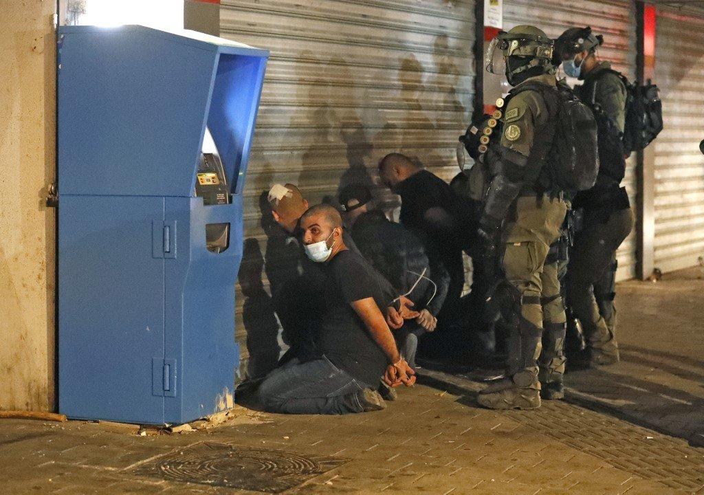 Israeli forces detain a group of Palestinian citizens of Israel in Lydd on 13 May 2021 after riots rocked the city (AFP)