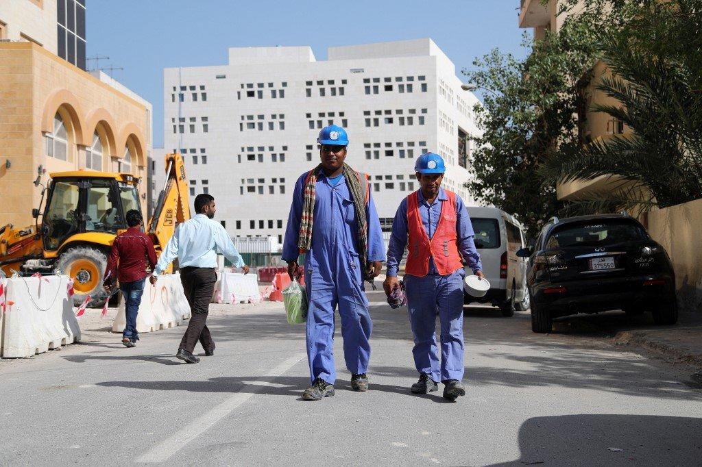 Migrant workers are seen walking next to a construction site in the Qatari capital Doha on 6 December 2016 (AFP)