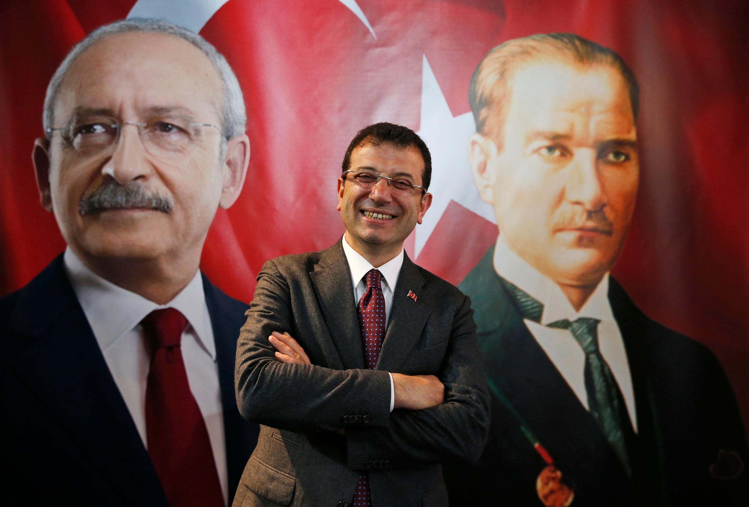 Backdropped by a poster of Kemal Kilicdaroglu, left, and Mustafa Kemal Ataturk, right, Ekrem Imamoglu poses for a photo in 2019 (AP)