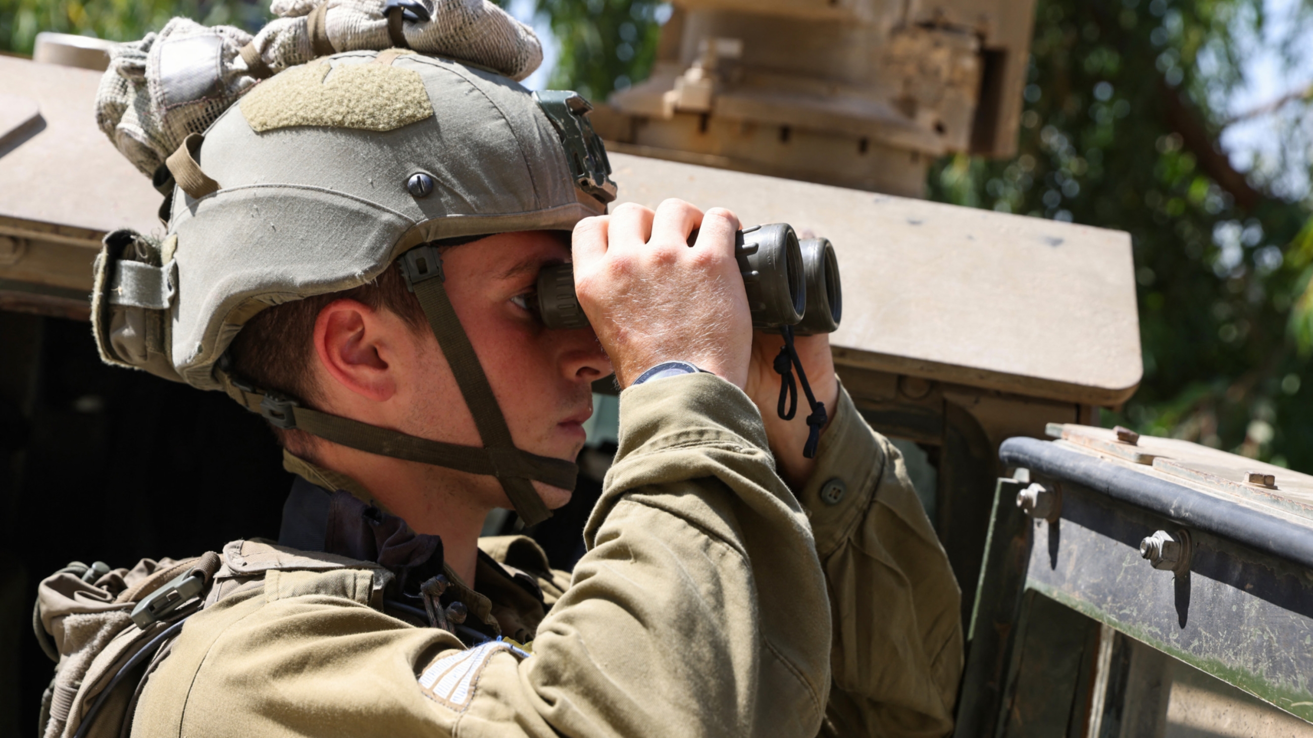 An Israeli soldier uses a binoculars during a patrol in the town of Al-Ghajar in the annexed Golan Heights bordering Lebanon, 6 July 2023 (AFP)