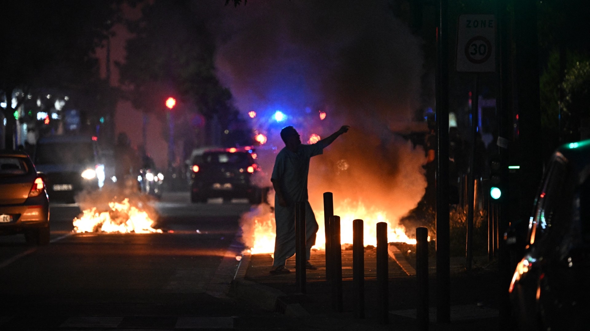 A man walks past a bonfire in a residential area during protests in Toulouse, southwestern France on 28 June 2023 (AFP)