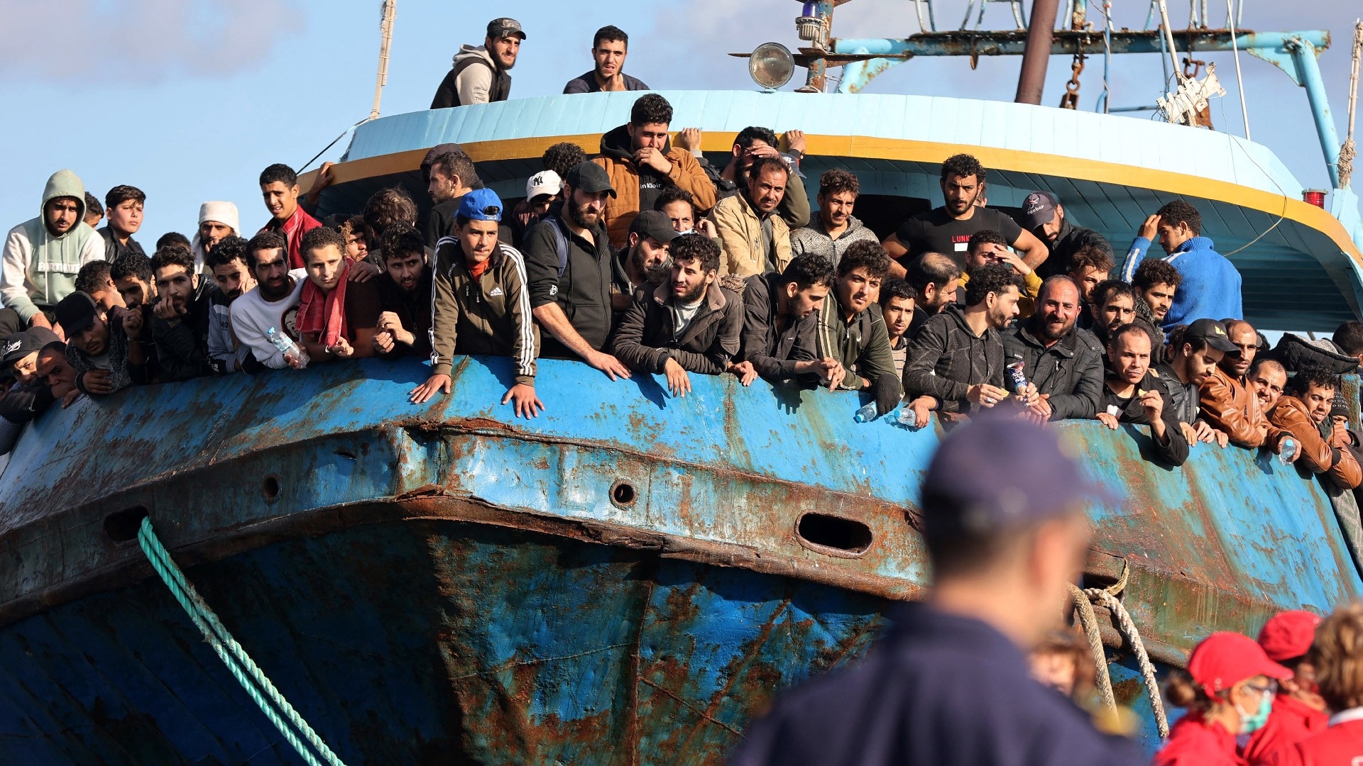 Rescued refugees and migrants stand aboard a boat at the town of Paleochora, southwestern Crete, on 22 November 2022 (AFP)