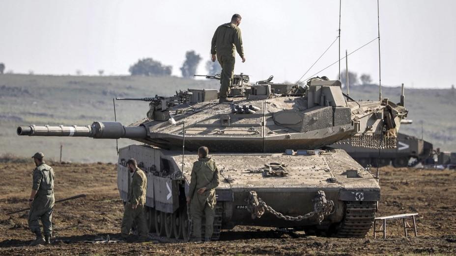 An Israeli soldier walks on a tank during a military exercise in the Golan Heights on 20 December 2022 (AFP)