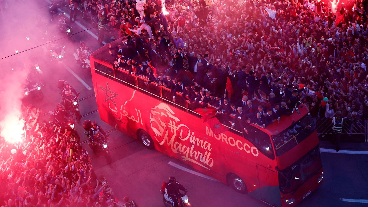 Morocco players on a bus touring the streets of Rabat as Morocco fans celebrate with flares during the parade on 20 December 2022.