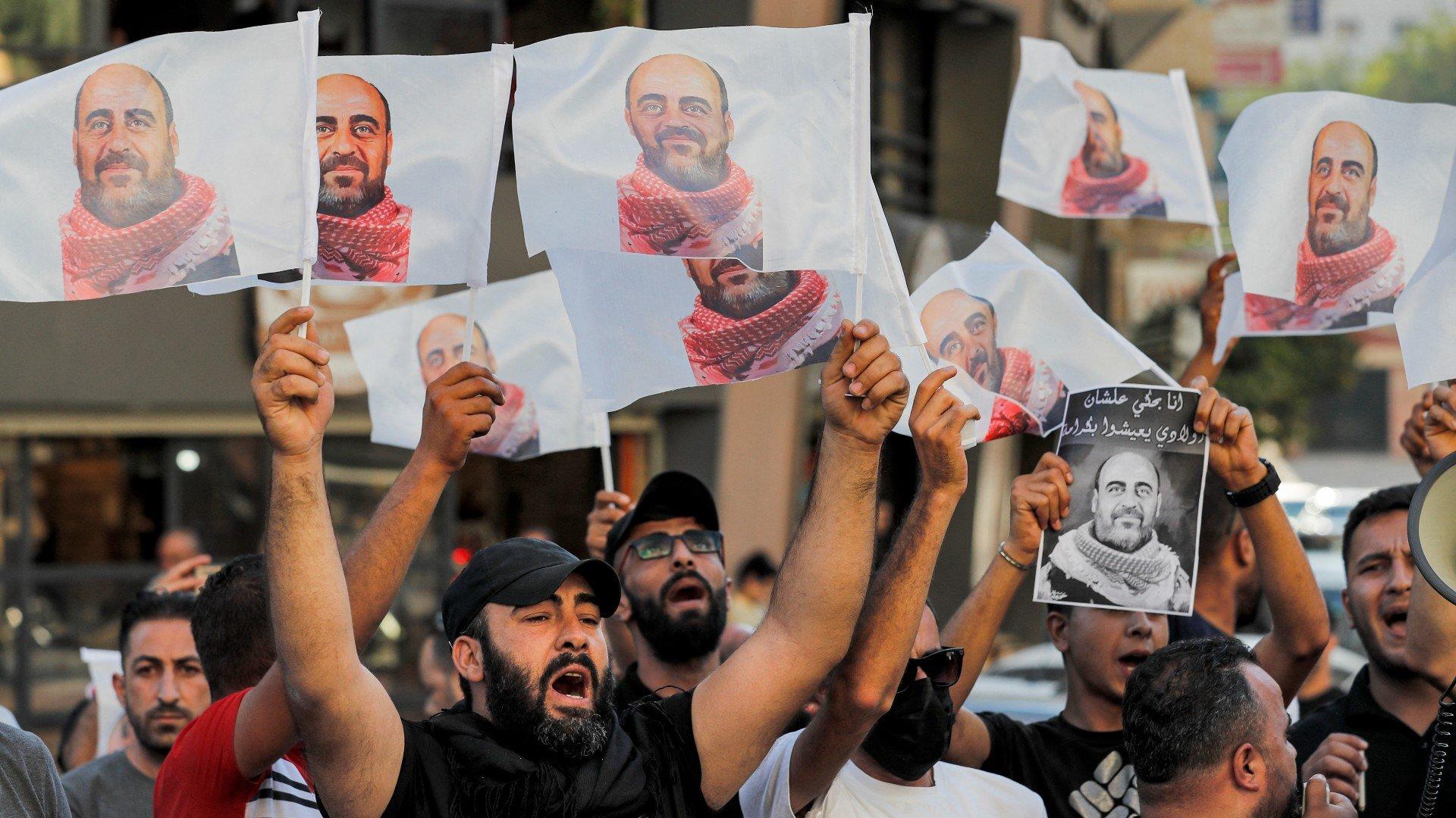 Demonstrators hold up images of murdered Palestinian activist Nizar Banat during a protest in the city of Hebron in the occupied West Bank on 13 July 2021 (AFP)