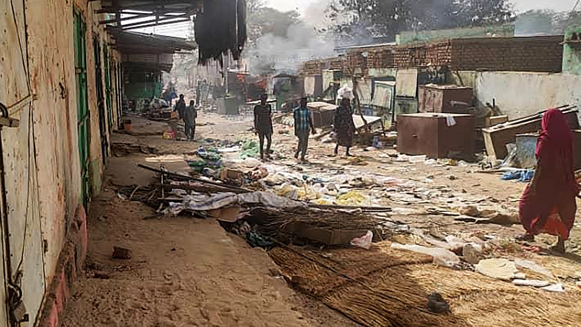 People walk among scattered objects in the market of el-Geneina, the capital of West Darfur, as fighting unfolded in Sudan on 29 April 2023 (AFP)