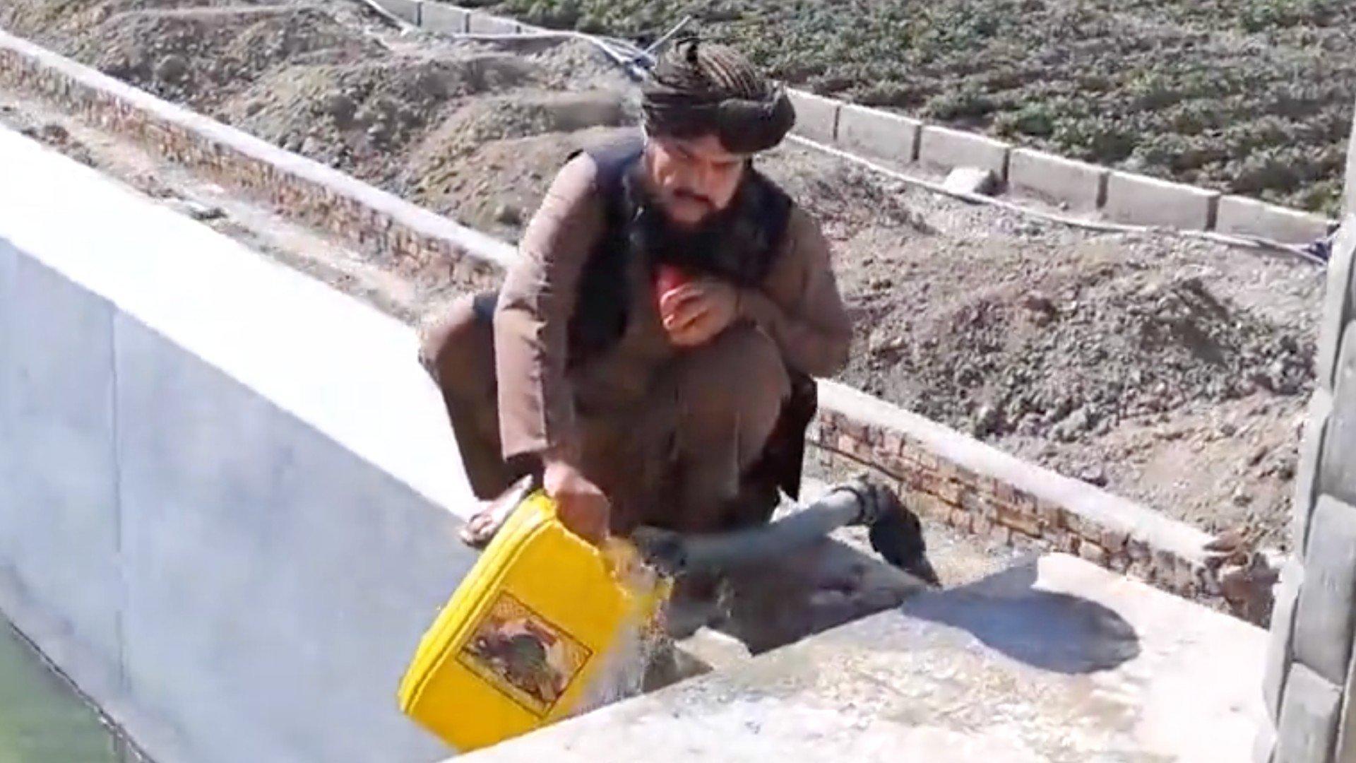 Taliban's General Mobin filling up a yellow plastic jug with water and offering it to Iranian President Ebrahim Raisi in a sarcastic video (Screengrab/social media)