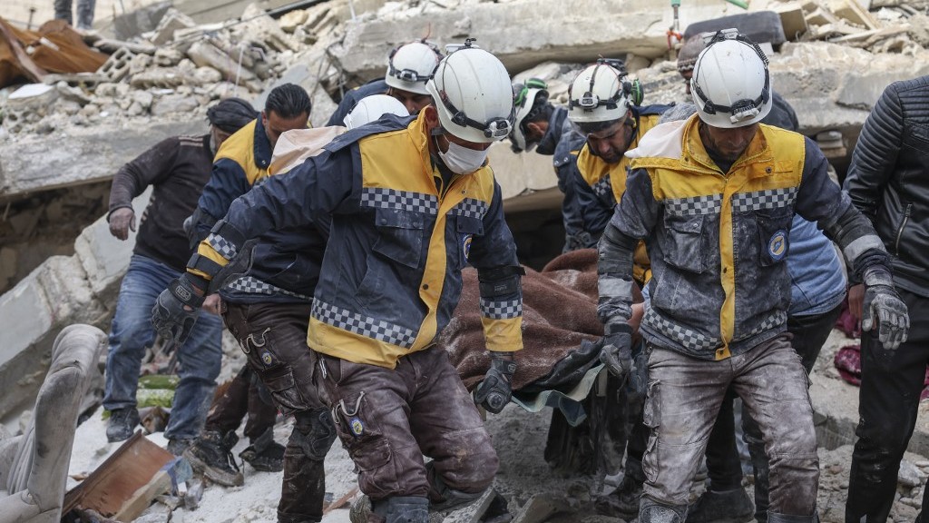 Members of the White Helmets transport a victim from the rubble of buildings in northwestern Idlib province on 7 February 2023 (AFP)