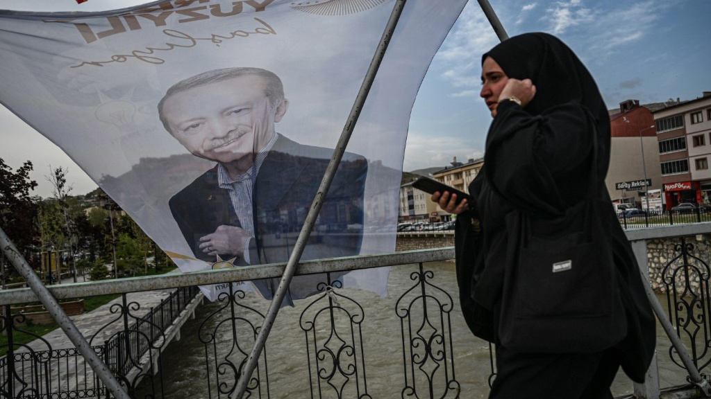 A woman walks past a flag of Turkish President Recep Tayyip Erdogan in Bayburt on 23 May 2023 (AFP)