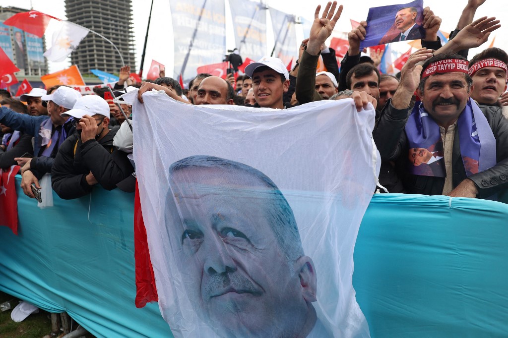 A supporter holds a banner featuring Turkish President Recep Tayyip Erdogan’s face during a campaign rally in Ankara on 30 April 2023 (AFP)