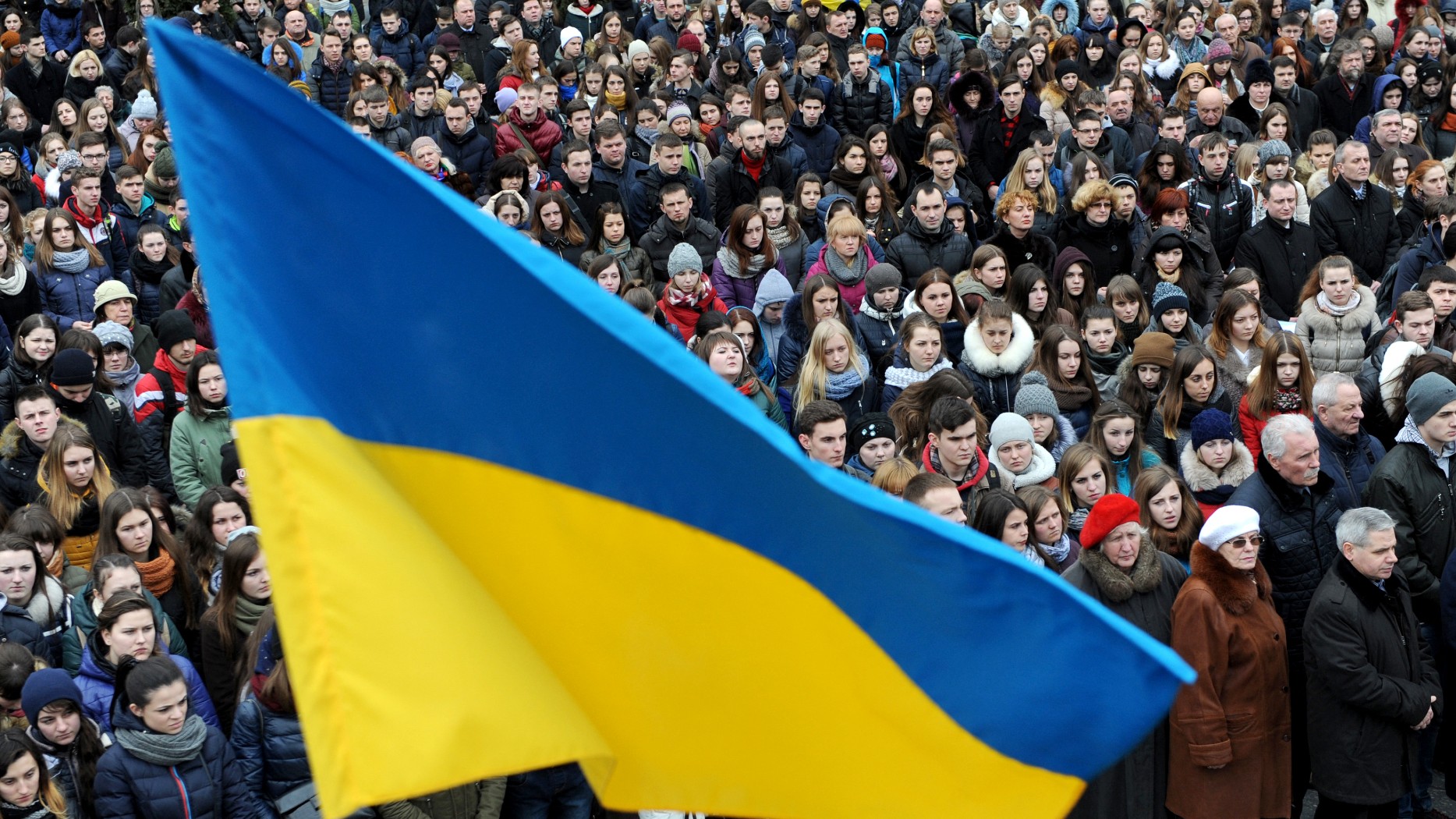 People hold a Ukrainian flag during a ceremony on February 19, 2016 in Lviv, western Ukraine to mark 2nd anniversary of an anti-government protest in 2014